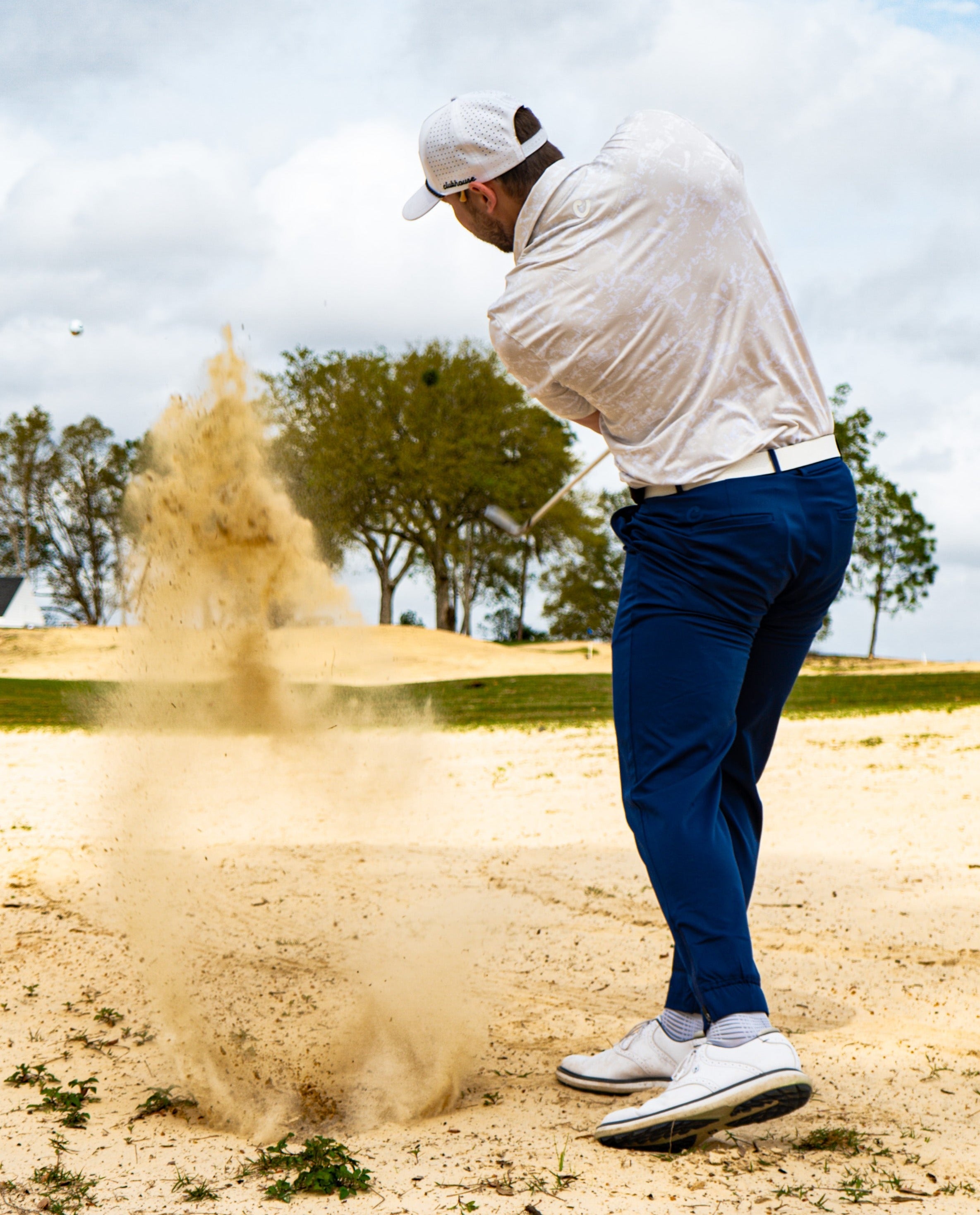 Golfer hitting sand shot in sandstorm polo